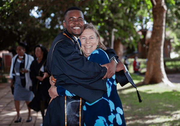 Graduate hugging woman outdoors