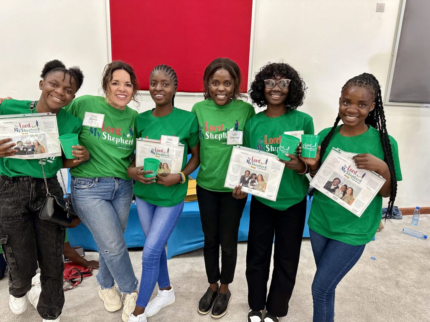 Women wearing green shirts, posing happily