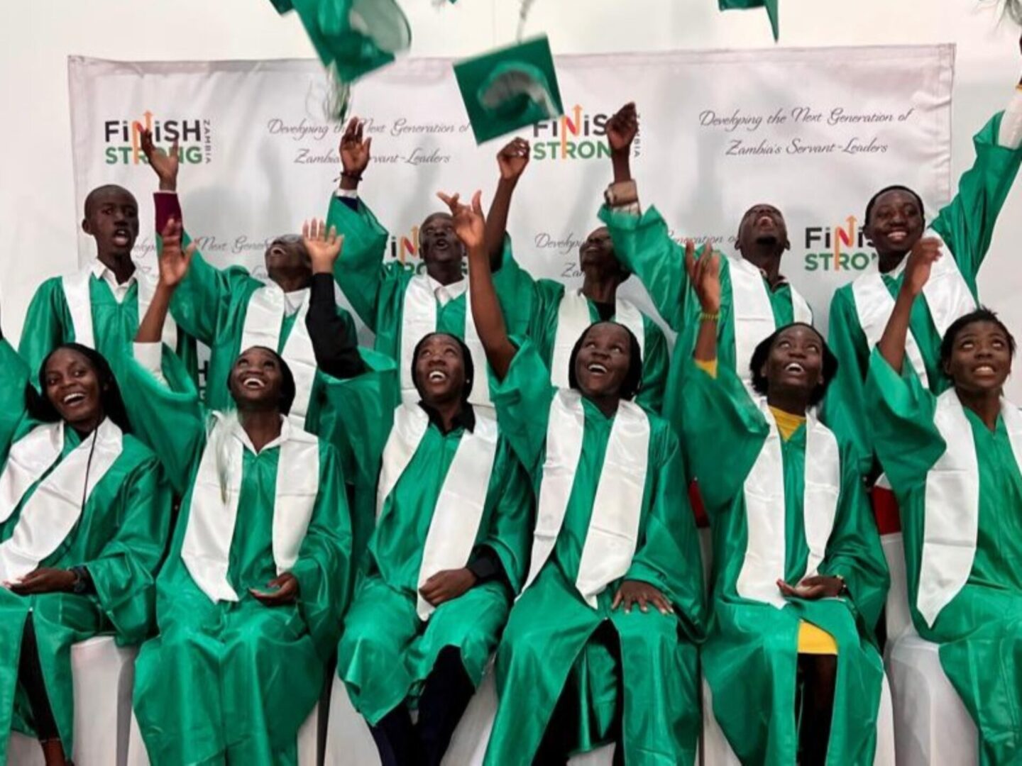 Graduates celebrating with raised hands and smiles.