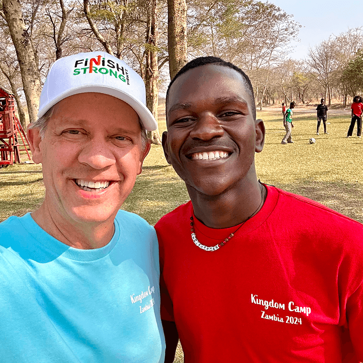 Two people smiling outdoors at camp