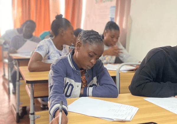 Students concentrating on their exam papers in a classroom.