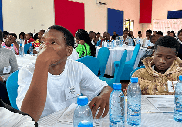 Young man attentively listening at a conference with water bottles on the table.